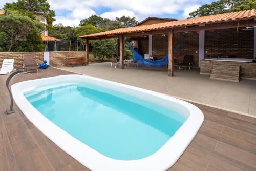 a large swimming pool on a patio with a swing at Chalé dos Campos in Vale do Capao