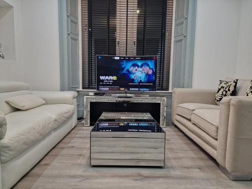 a living room with two couches and a flat screen tv at Boutique villa newly refurbished Dundee in Dundee
