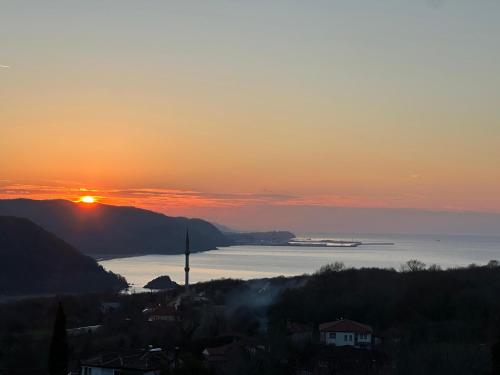 a sunset over the water with a cruise ship in the distance at Mugada Deluxe Bungalov in Güzelcehisar