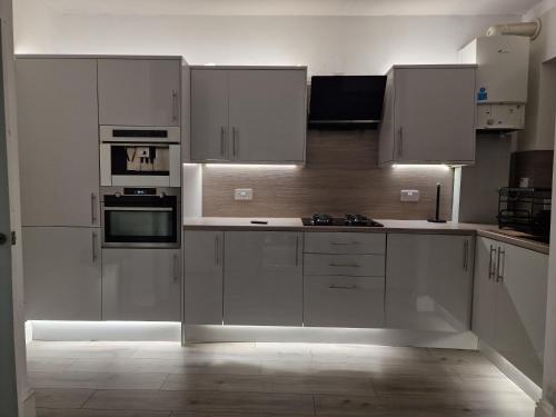 a white kitchen with white cabinets and appliances at Boutique villa newly refurbished Dundee in Dundee