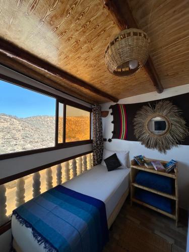 une chambre avec un lit et une grande fenêtre dans l'établissement Ami D'or Hostel, à Taghazout