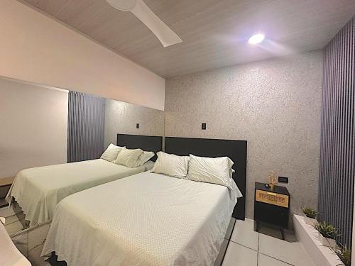 a bedroom with two beds with white sheets at Ken's lower apartment in Quepos