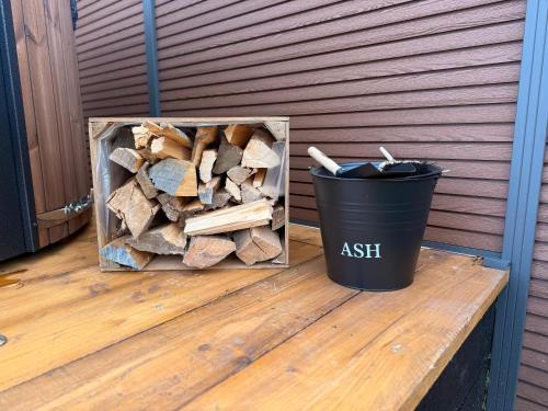 a black trash can sitting next to a pile of wood at Luxury Glamping Pods at Pool House Farm 