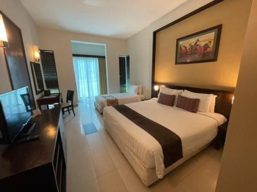 Una habitación de hotel con dos camas y un televisor de pantalla plana. en Hotel Felda Residence Tanjung Leman, en Jemaluang