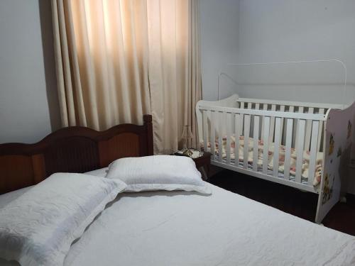 a bedroom with two beds and a baby crib at Aunt A CASA DOS SONHOS DA TIA LETÍCIA in Miguel Pereira