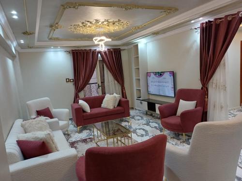 - un salon doté d'un mobilier rouge et blanc et d'une télévision dans l'établissement الفريده شقة فندقية, à Mudīrīyah