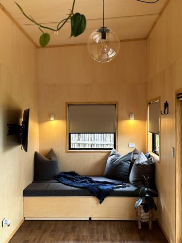 a couch in a room with a window at Hahei Tiny Home - Outdoor Bath in Hahei