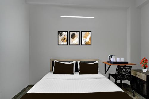 a bedroom with a bed and a table with a chair at Hotel O Shamshabad Station Formerly Grand Vista Hotel in Shamshabad