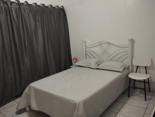 Un dormitorio con una cama blanca y una silla. en Espaço Ideal Apartamento 2 Quartos, en Cascavel