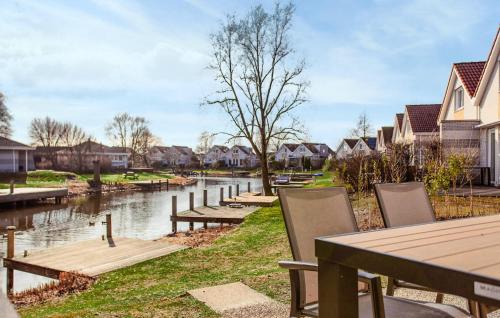 Una mesa y sillas al lado de un río con casas. en Nice Home In Makkum With Lake View, en Holle Poarte