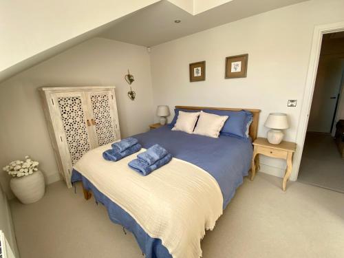 a bedroom with a bed with blue pillows on it at Boutique Burnham Market Cottage in Burnham Market