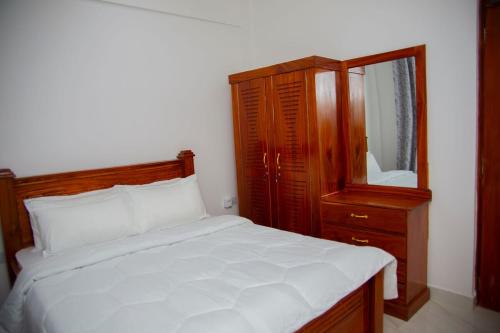 a bedroom with a bed and a dresser and a mirror at Havah Zanzibar Home in Mwanakwerekwe