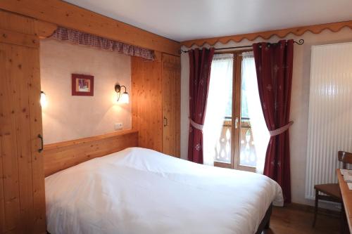a bedroom with a white bed and a window at Hôtel Belalp in Châtel