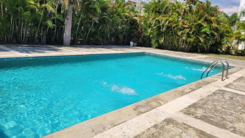 a swimming pool with blue water and palm trees at Beautiful apartment near STGO airport in Santiago de los Caballeros