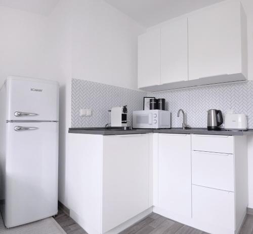 a kitchen with white cabinets and a refrigerator at nestup - Zentrales Apartment mit Boxspringbetten, Smart-TV und ausgestatteter Küche in Kassel