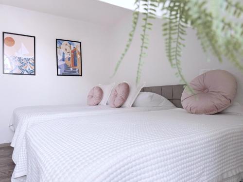 a bedroom with a white bed with pink pillows at nestup - Zentrales Apartment mit Boxspringbetten, Smart-TV und ausgestatteter Küche in Kassel