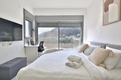 una camera da letto con un grande letto bianco con una grande finestra di Luxe on the BEACH By LIME a Haifa
