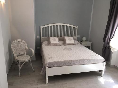 ein Schlafzimmer mit einem weißen Bett und einem Stuhl in der Unterkunft Camere La Forgia in Lazise