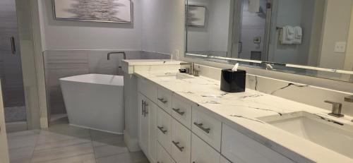 y baño con 2 lavabos, bañera y espejo. en Modern & Luxurious 3BR Retreat!, en Orlando