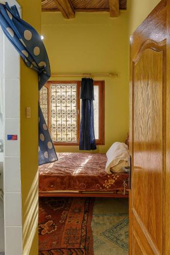 a small bedroom with a bed and a window at Riad restaurante Étoile dades Camping in Imdiazene