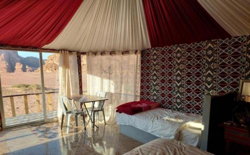 a bedroom with a bed and a table with a view at Wadi Rum Magic Stars in Wadi Rum