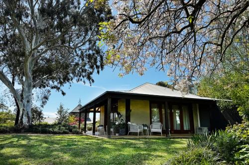 a house with a porch with chairs and a tree at The Pavilion Yarra Valley luxury country retreat in Coldstream