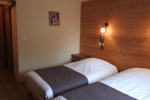 a bedroom with two beds and a wooden wall at Hôtel Belalp in Châtel