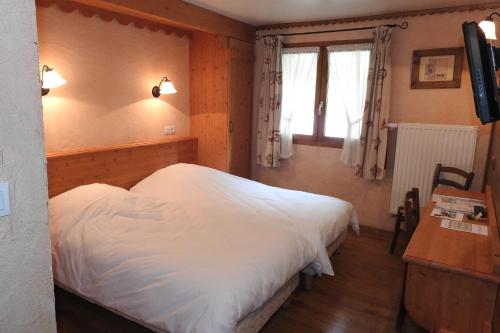 a bedroom with a white bed and a window at Hôtel Belalp in Châtel