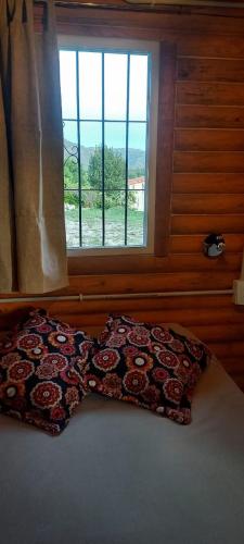 a pillow on a bed in front of a window at Los Espinillos Cabaña Exclusiva in Huerta Grande