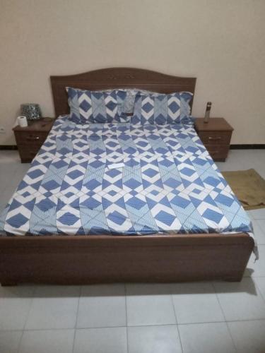 - un lit avec une couette et des oreillers bleus et blancs dans l'établissement Hébergement 4 pièces Dakar, à Darou Rhamane