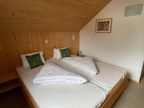 a bed with white sheets and green pillows in a room at The Laerch in Hohentauern
