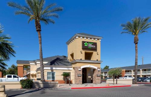 a hotel with palm trees in front of a building at Extended Stay America Select Suites - Phoenix - Airport - E Oak St in Phoenix
