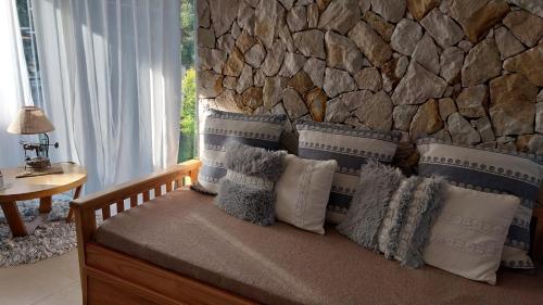 a bed with pillows and a stone wall at Arena de Mar depto A in Mar de las Pampas
