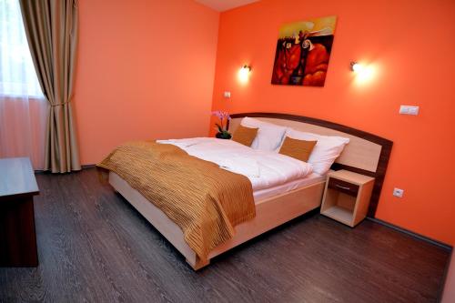 a bedroom with a bed with an orange wall at Bartal Rodinné Vinárstvo in Šamorín