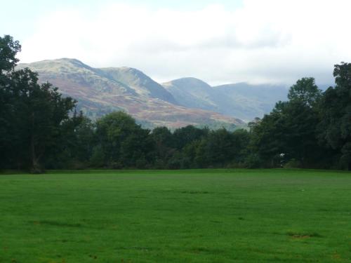a large green field with mountains in the background at 3 Cambridge Villas in Ambleside