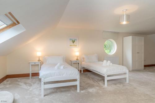 two white beds in a room with a window at Helyg in Penmaen-mawr