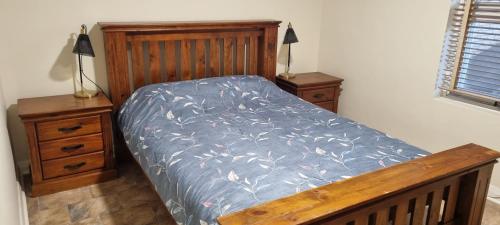 a bed with a blue comforter and two night stands at River Cottage at Mannum in Mannum