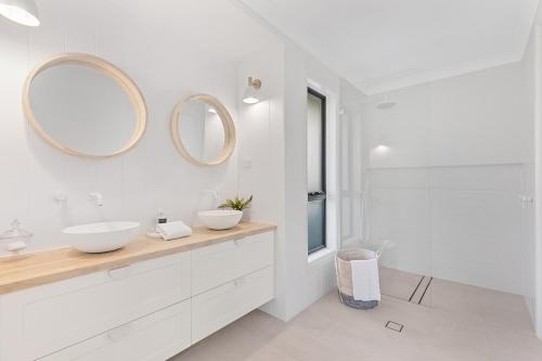 ein weißes Badezimmer mit zwei Waschbecken und zwei Spiegeln in der Unterkunft Whitepepper Cottage in Pokolbin