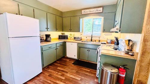a kitchen with green cabinets and a white refrigerator at Jacuzzi, game room near Lassen and Hat Creek in Burney