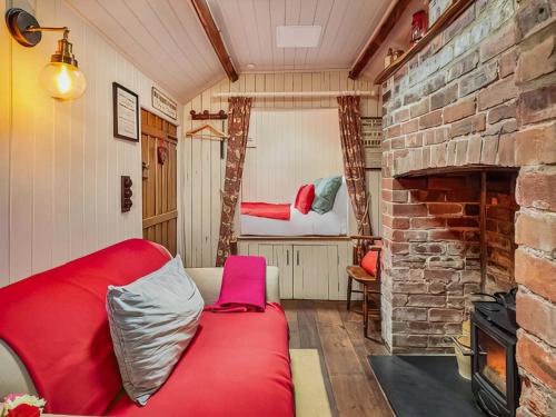 a living room with a red couch and a brick fireplace at The Cabin in Llangadog