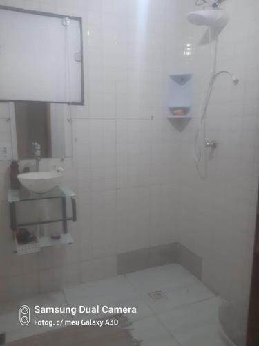 a white bathroom with a sink and a toilet at Casa sobrado in Arraial do Cabo