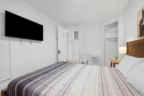 a white bedroom with a bed and a flat screen tv at Pittsburgh Shadyside 1C Spacious and Cozy Private Bedroom with Shared Bathroom in Pittsburgh