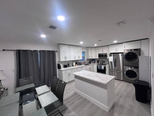 a kitchen with white cabinets and a table and appliances at Place to stay in Hallandale Beach