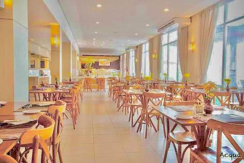 a restaurant with wooden tables and chairs and windows at Apartamento Particular à Beira do Mar e pé na areia em Acqua Resort Beach Park in Aquiraz