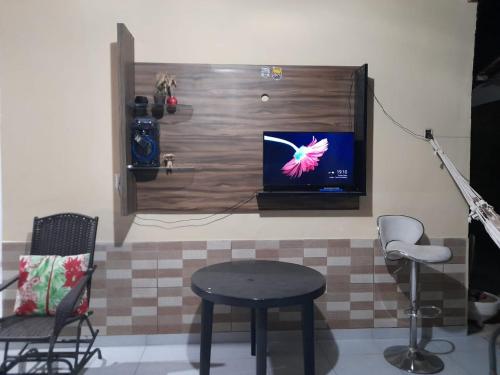een kamer met een tafel en een tv aan de muur bij Hospedaria Temporarte in Piranhas