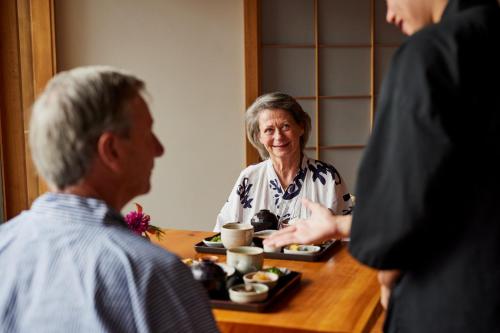 a woman sitting at a table with a plate of food at Shizuka Ryokan Japanese Country Spa & Wellness Retreat in Hepburn Springs