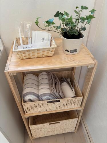 a wooden shelf with towels and a potted plant at ゲストハウスharu in Shingū