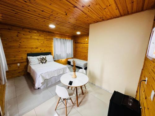 a bedroom with a bed and a table and chairs at Cabanas Coimbra in Urubici
