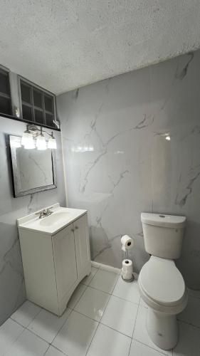 a white bathroom with a toilet and a sink at Jacuzzi Hideaway in San Juan