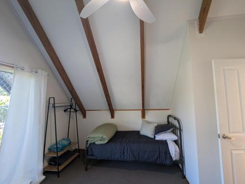 ein kleines Bett in einem Zimmer mit einer Decke in der Unterkunft Wooli Cottage Retreat in Wooli